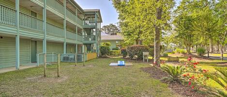 A courtyard with a GoSports table, a wooden deck, and a building with multiple balconies.