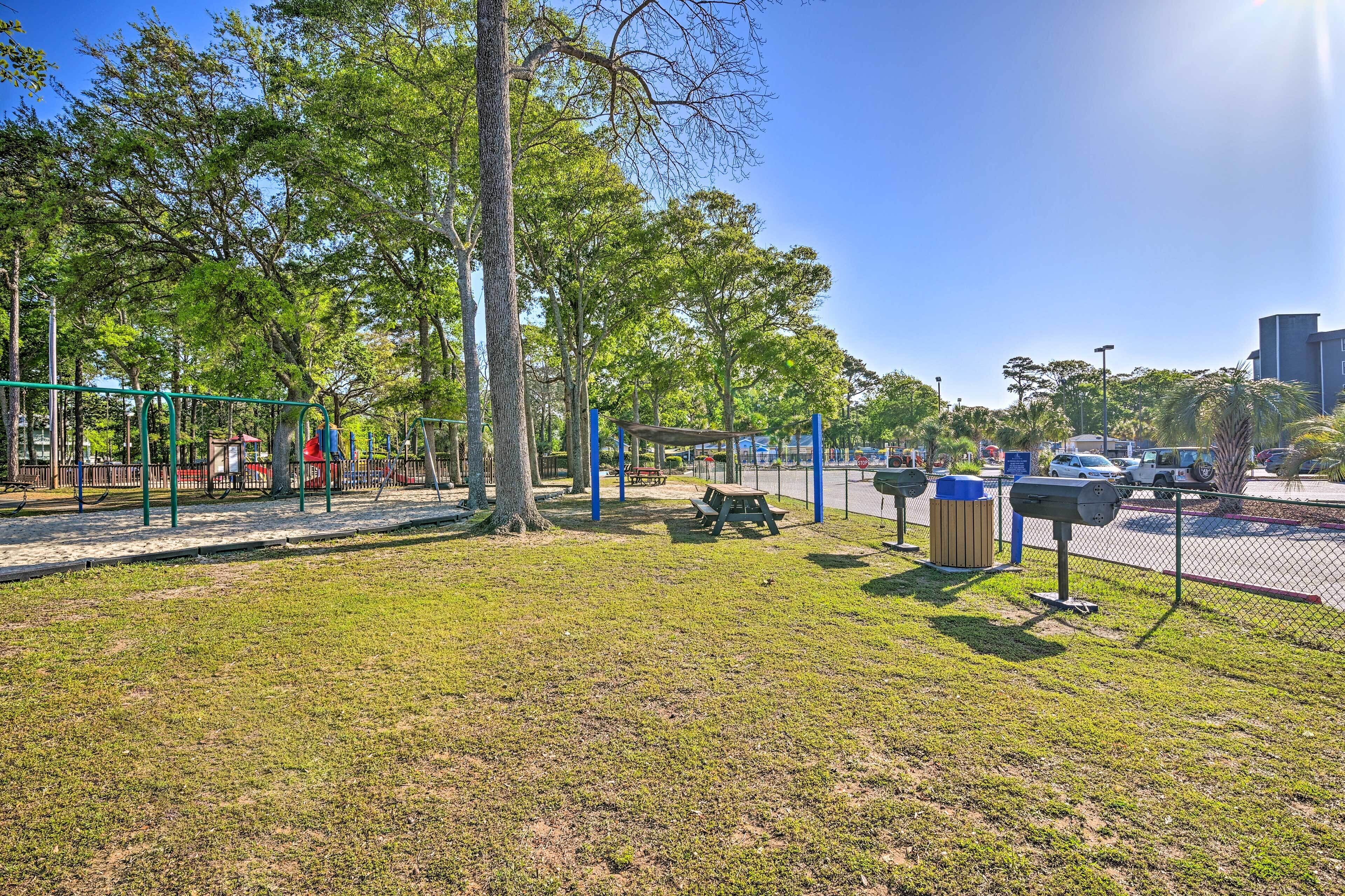 Ein Park mit Spielgeräten, Picknicktischen und Mülleimern.