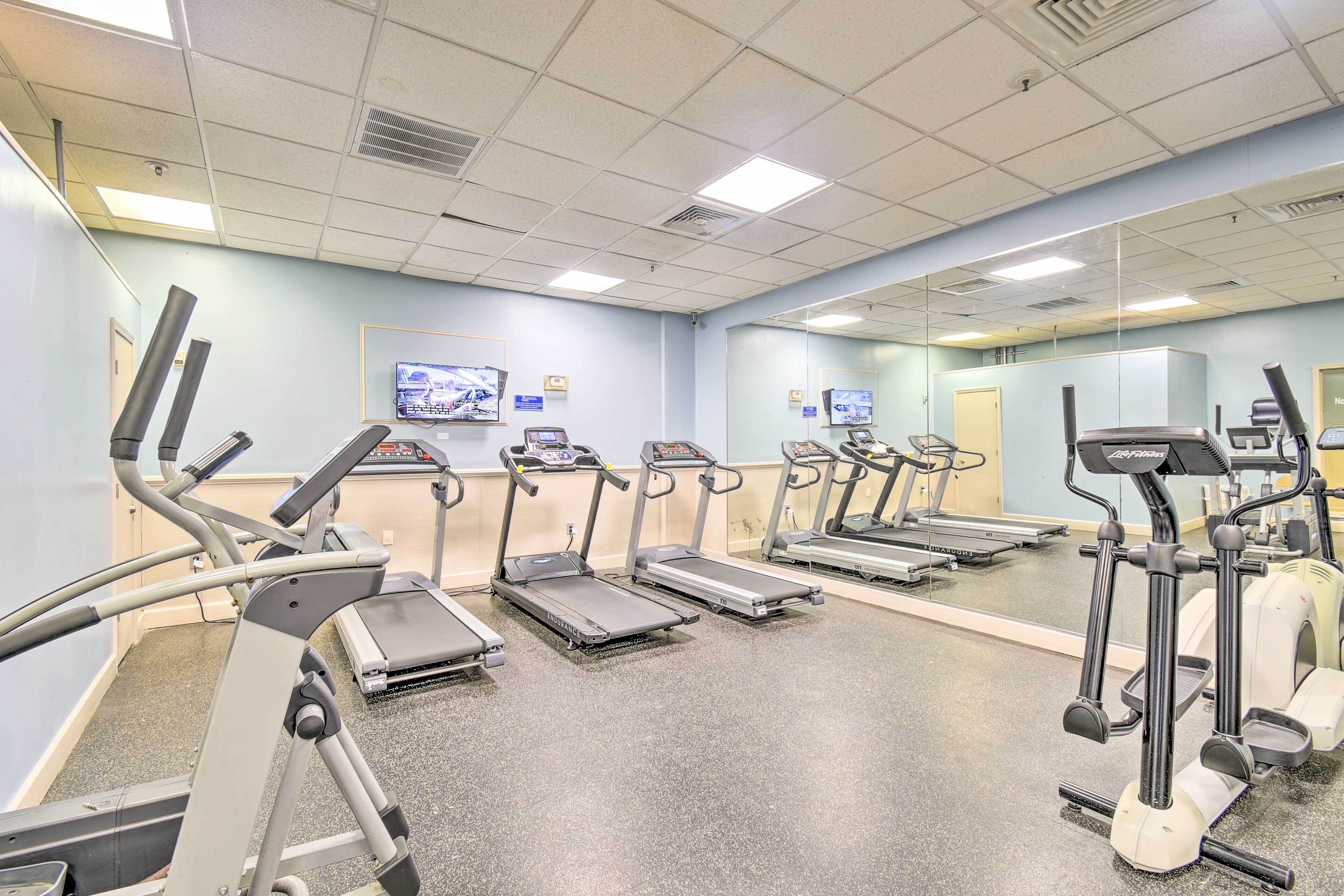 Ein Fitnessraum mit mehreren Laufbändern, Ergometer und Spiegel an den Wänden.