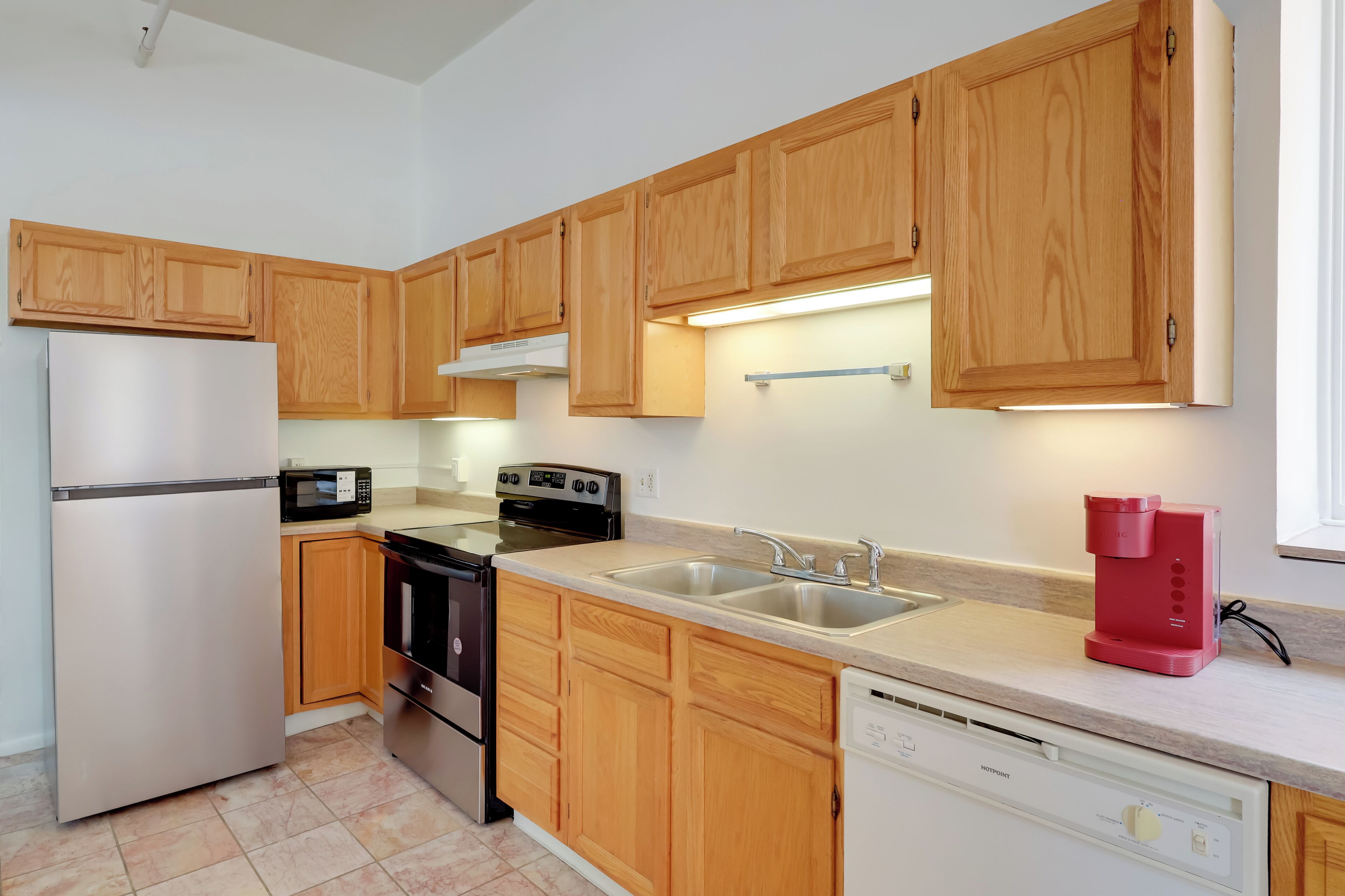 A modern kitchen with wooden cabinets, stainless steel appliances, and a dishwasher.