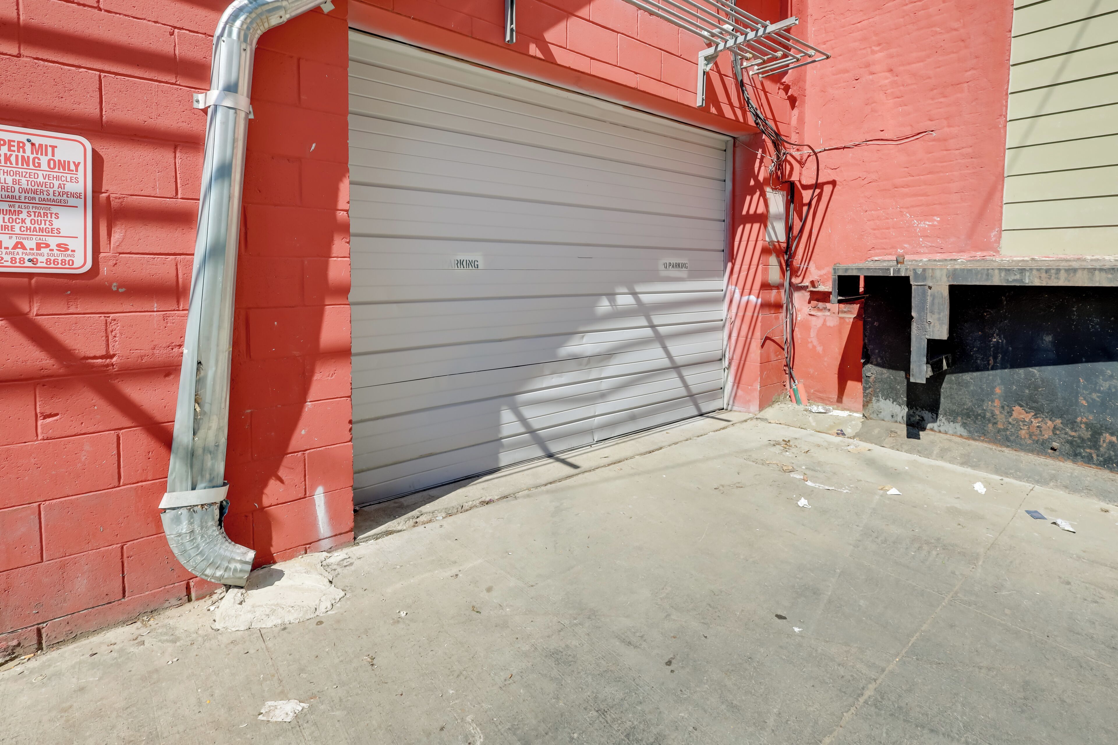 A closed garage door with a metal ladder and a sign on the wall.