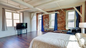 Une chambre d’hôtel avec un grand lit, une télévision et un mur en briques.