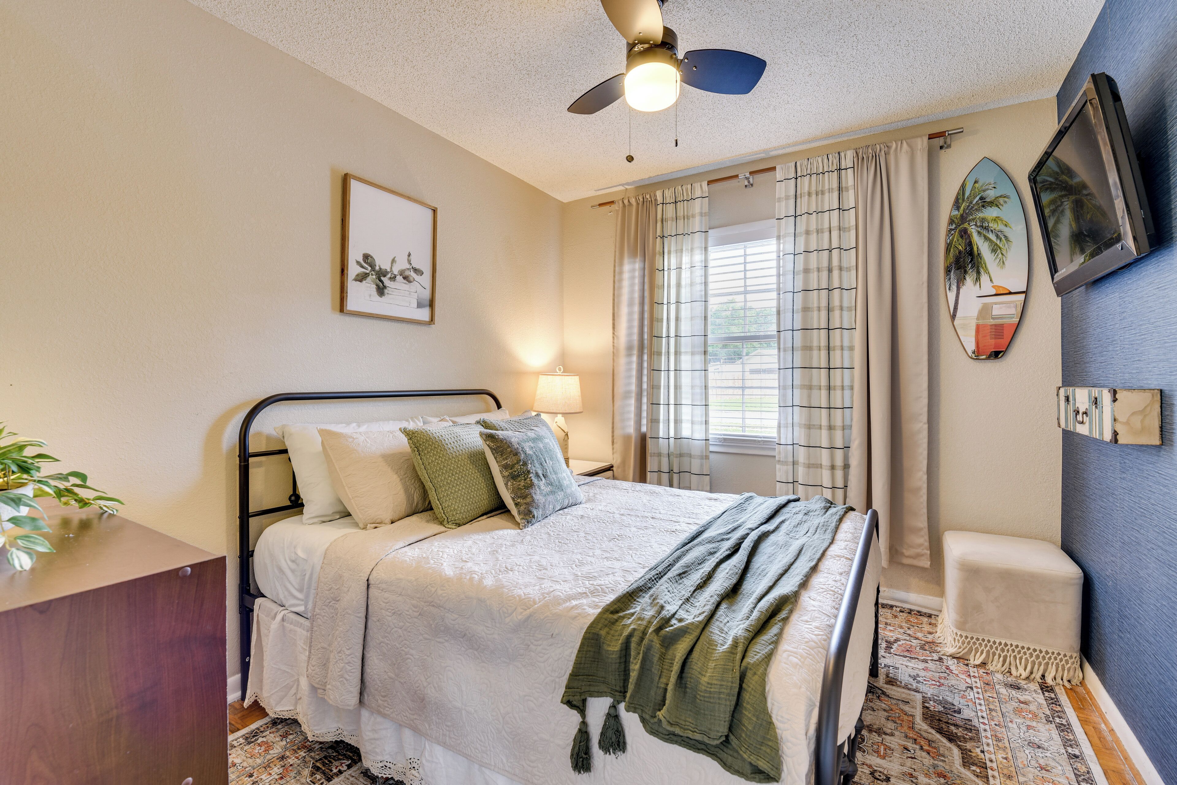 A bedroom with a bed, bedside table, lamp, and a ceiling fan.