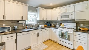 Una cocina moderna con armarios blancos, un fregadero de acero inoxidable, un microondas y una estufa.