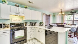 A kitchen with white cabinets, a stove, and a dishwasher. There is a dining area with a table and chairs. - Balloon Fiesta Base in Abq's Ventana Ranch (Albuquerque)