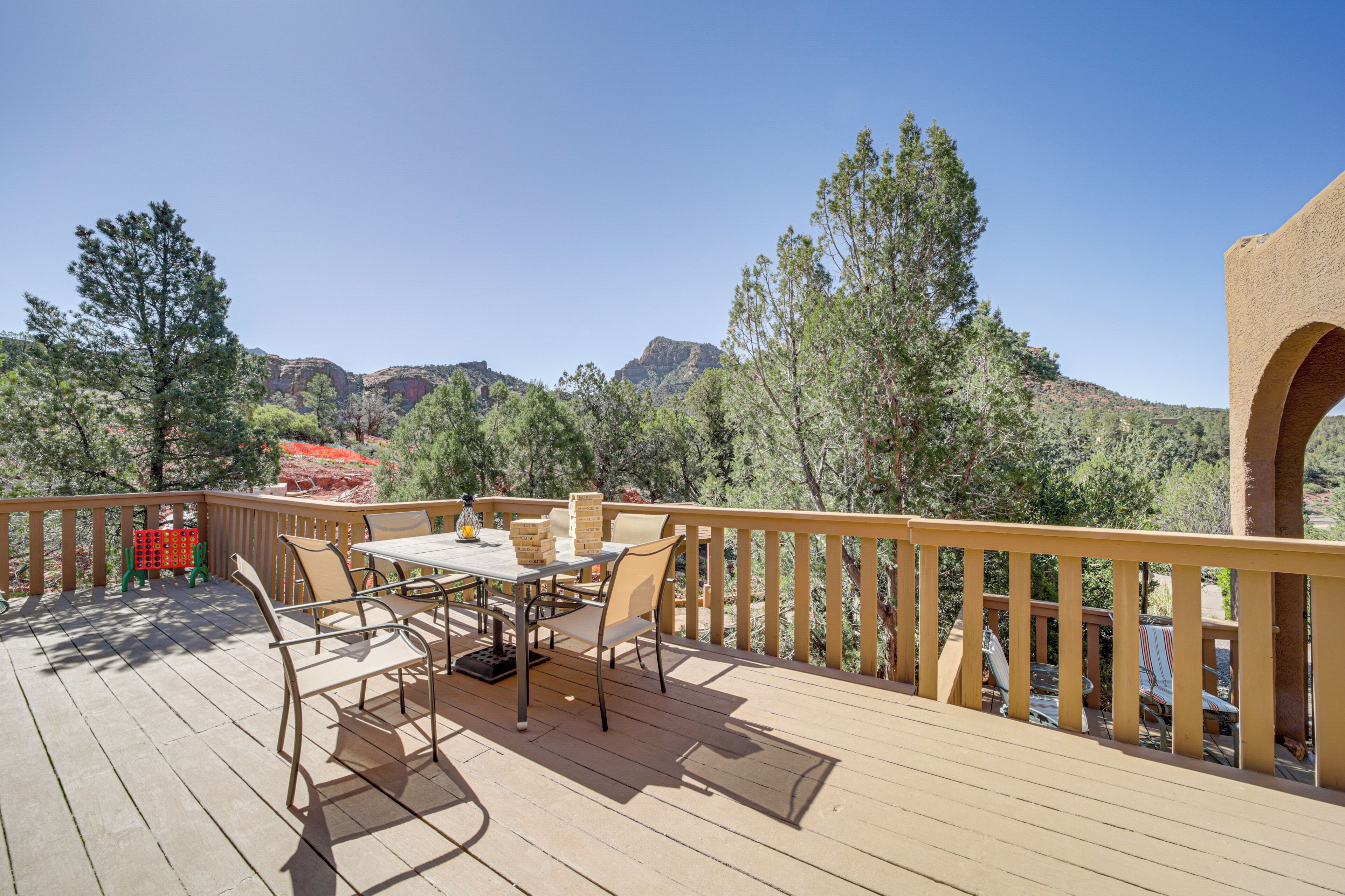 Une terrasse en bois, aménagée avec du mobilier d’extérieur, notamment une table et des chaises, qui offre une vue sur un paysage montagneux.