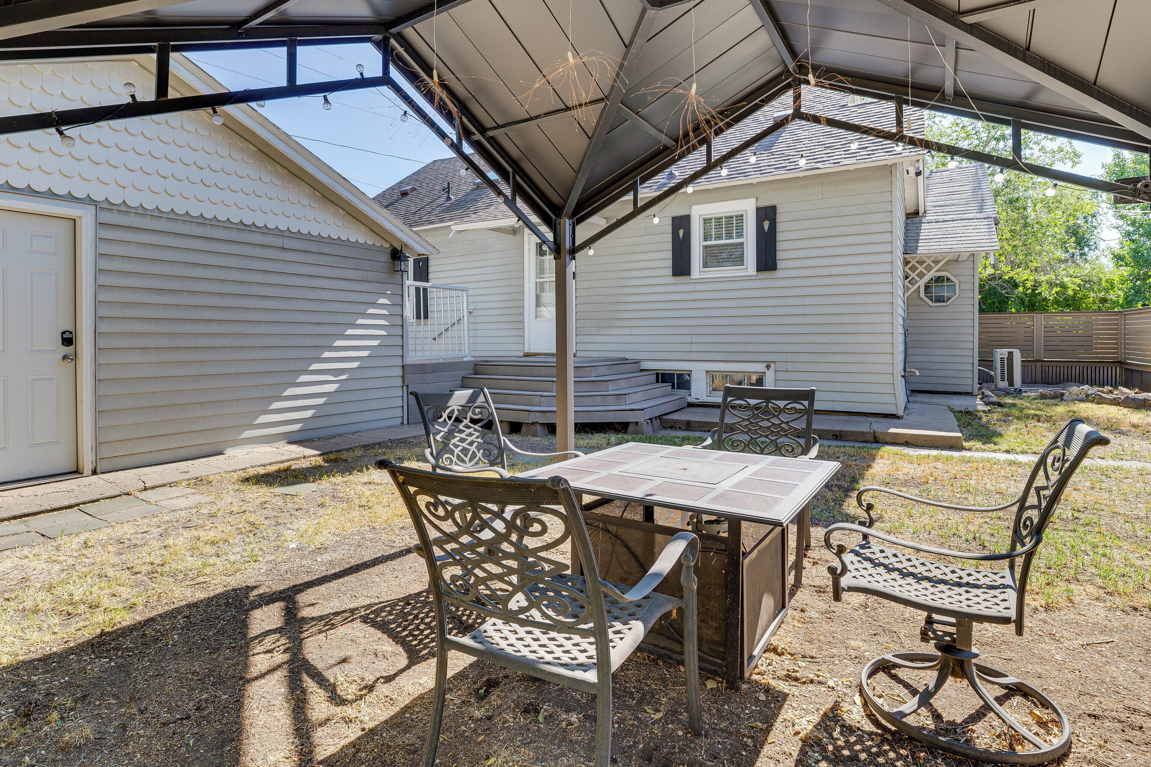 A covered patio area with a table and chairs, a small deck, and a house in the background.