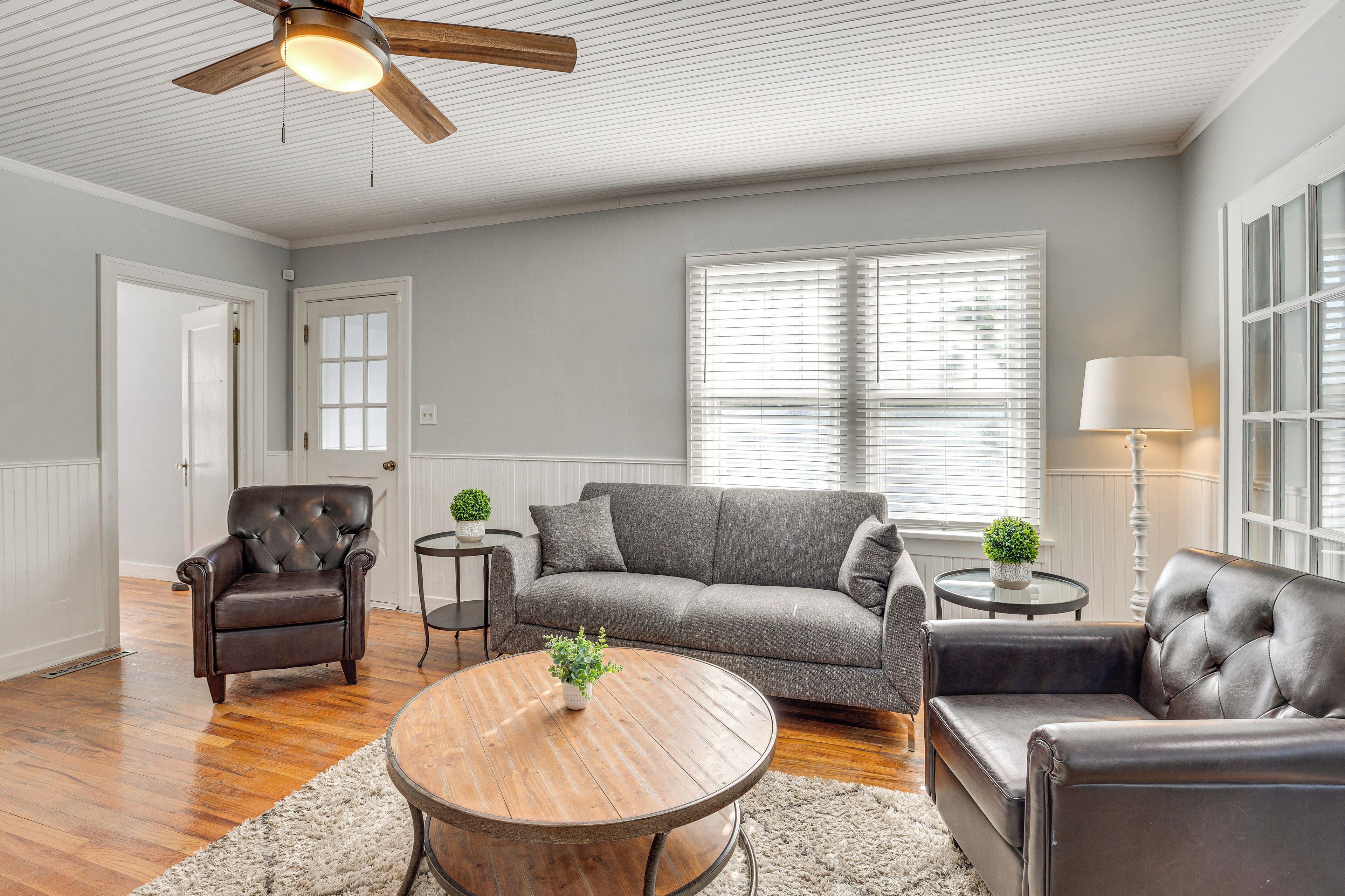 A living room with a wooden coffee table, a leather armchair, a grey sofa, and a ceiling fan.