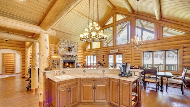 A spacious log cabin interior with a large kitchen island, wooden floors, and a chandelier. - 'nonna's Cabin' Family Mtn Retreat in Westcliffe! (Westcliffe)