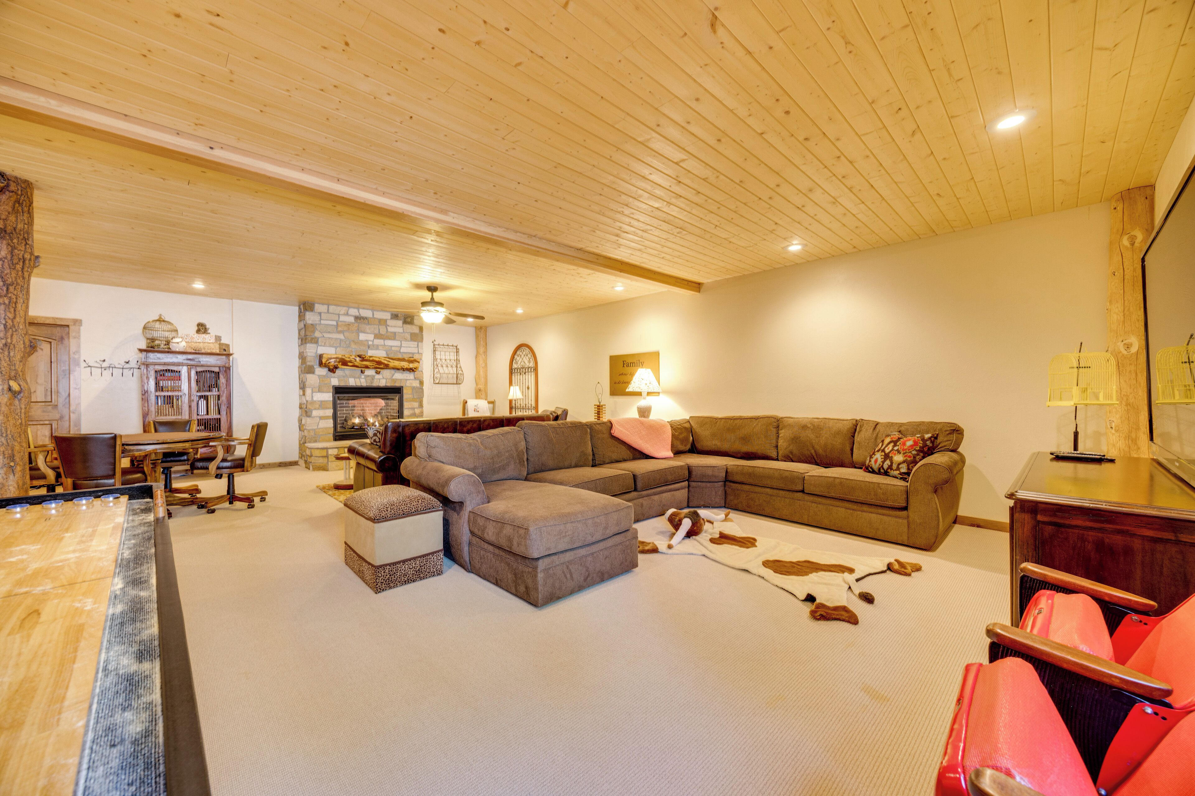 A cozy living room with a sectional sofa, a dining area with a wooden table, and a fireplace.