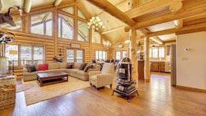 A spacious log cabin interior with a large living area, a fireplace, and a kitchen visible through an open doorway. - 'nonna's Cabin' Family Mtn Retreat in Westcliffe! (Westcliffe)