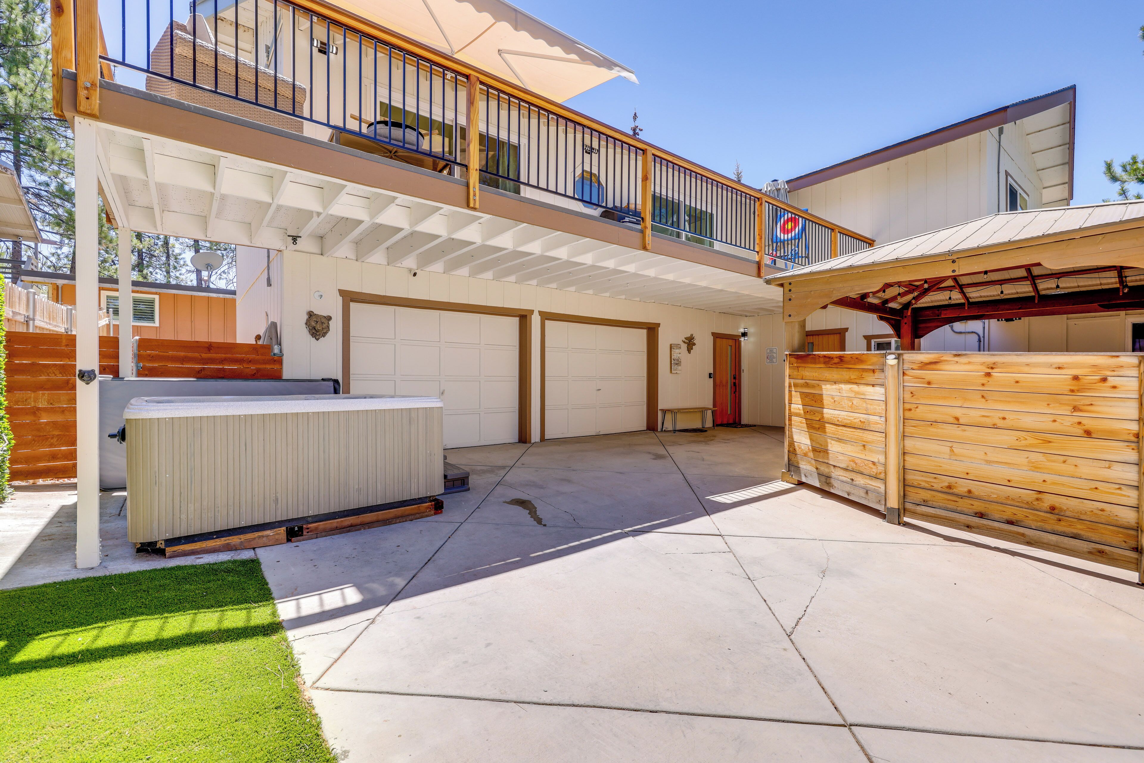 A two-story house with a covered patio, a hot tub, and a garage.