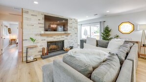Ein modernes Wohnzimmer mit Kamin aus Stein, einem großen Flachbildfernseher und einem grauen Sofa.