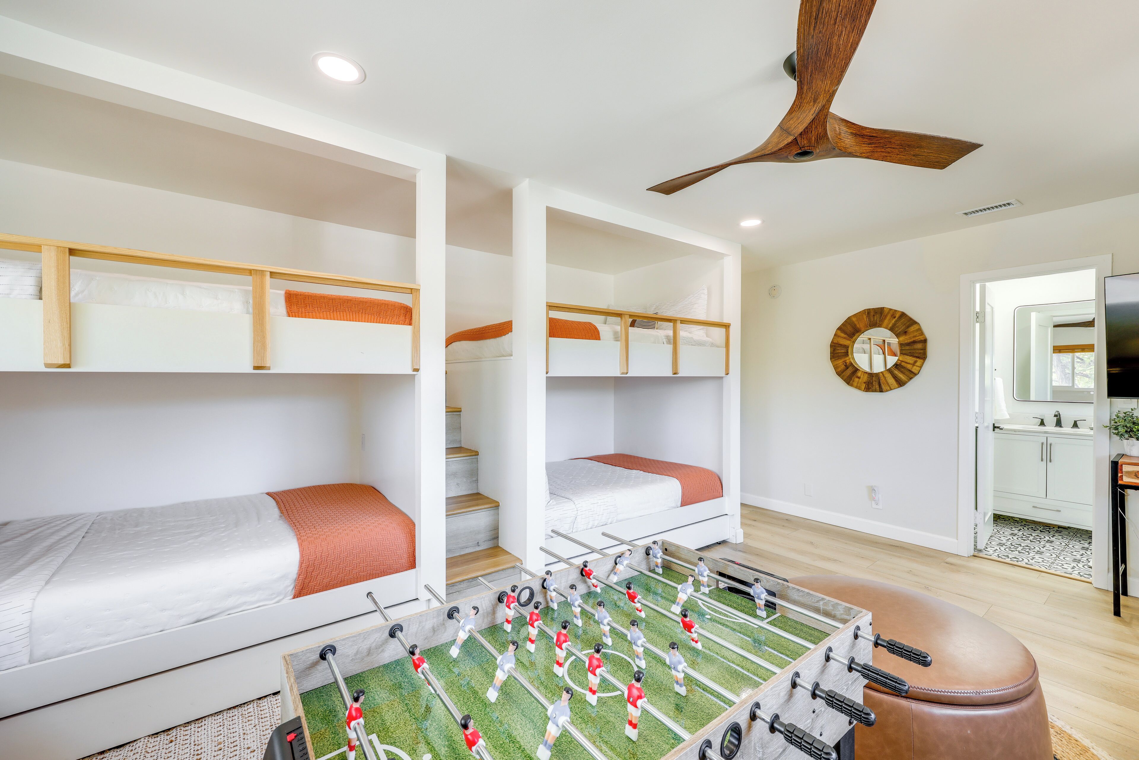 Een kamer met stapelbedden, een tafelvoetbaltafel en een plafondventilator.