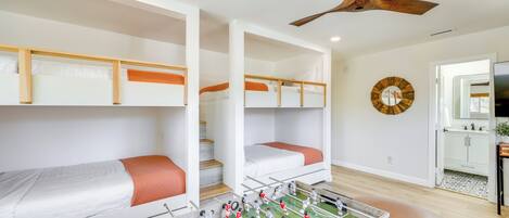 Een kamer met stapelbedden, een tafelvoetbaltafel en een plafondventilator.