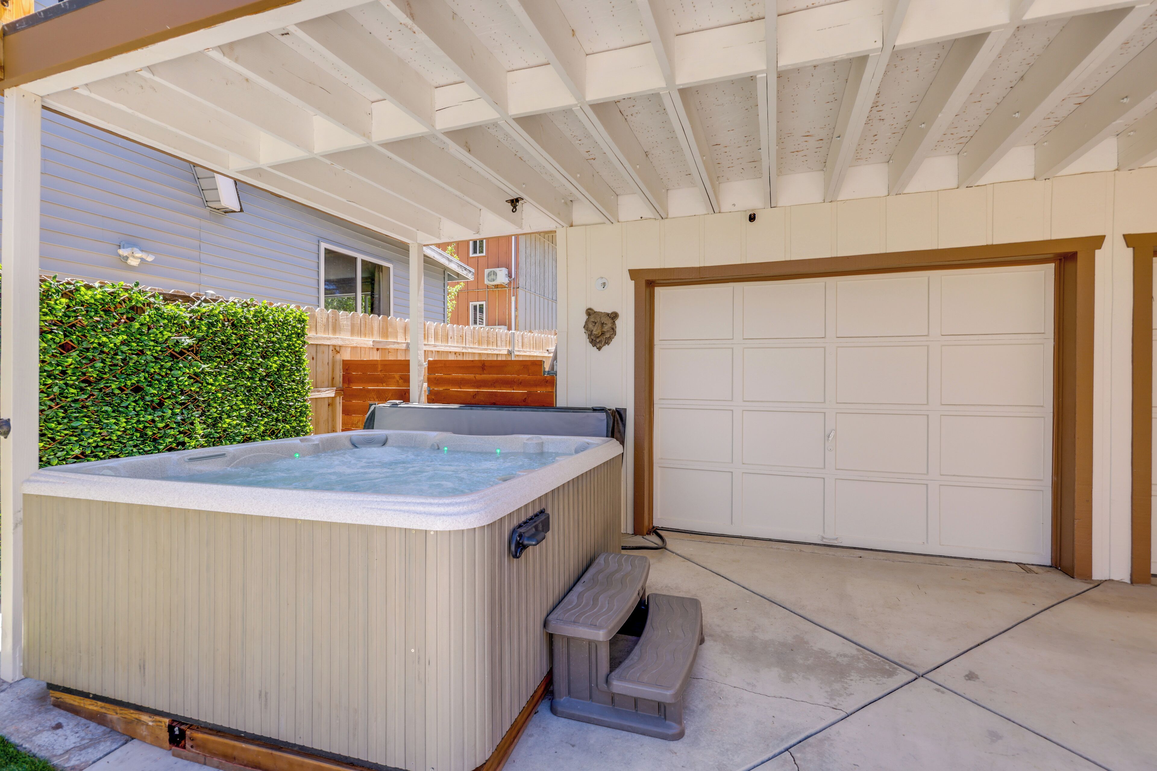 Un espacio al aire libre cubierto con un jacuzzi, una banca de madera y una puerta de garaje.