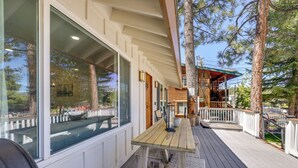 Un'area esterna coperta con una veranda in legno, un tavolo e sedie, e ampie finestre.