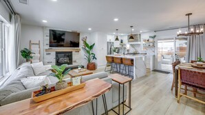 Un soggiorno moderno con divano, tavolino e televisione. È presente una zona cucina con tavolo e sedie.