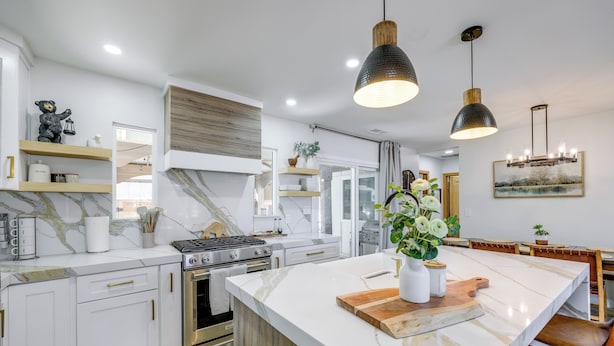 Una cucina moderna con mobili bianchi, un'isola grande e luci a sospensione.