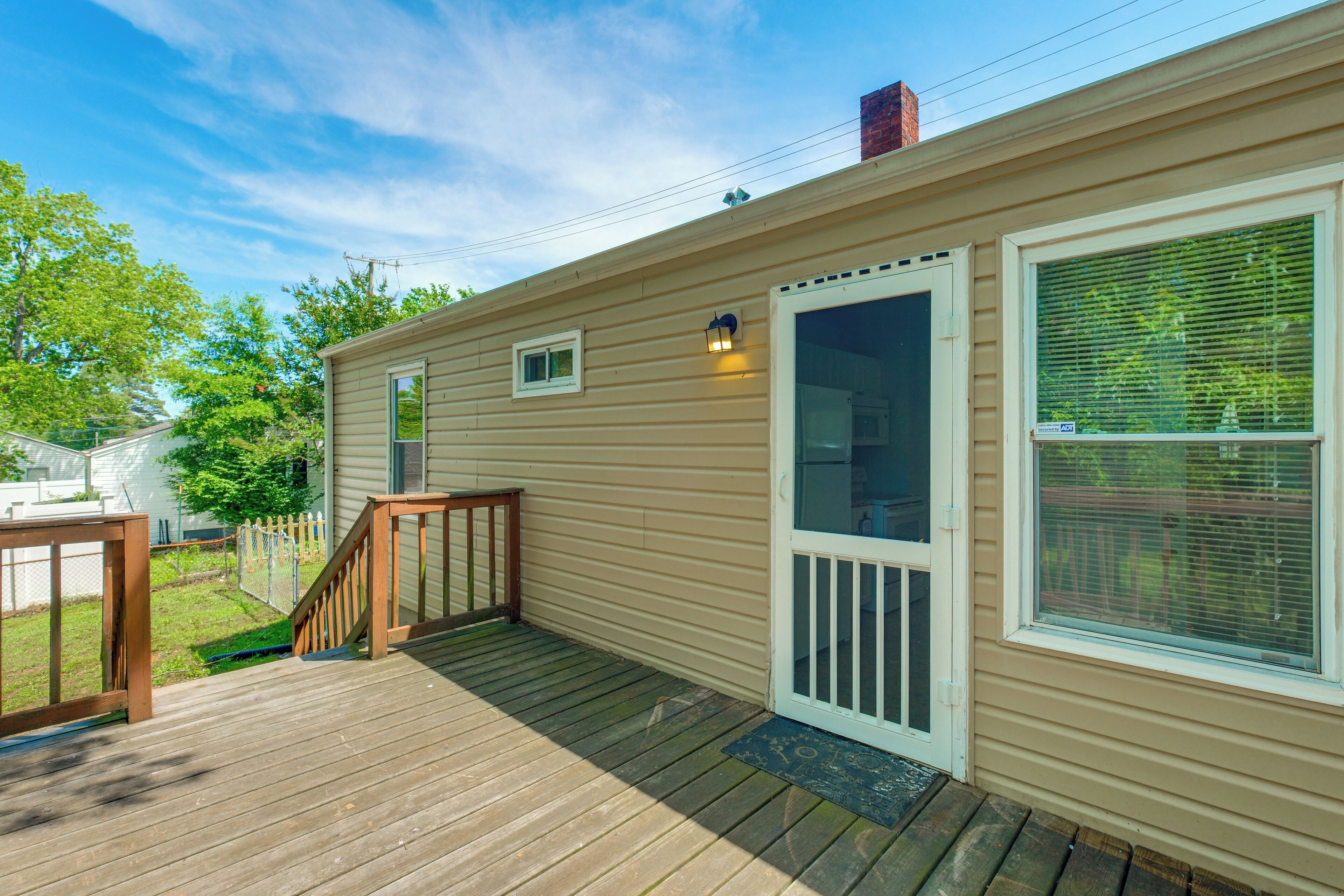 A single-story mobile home with a wooden deck, a front door with a glass panel, and a small window.