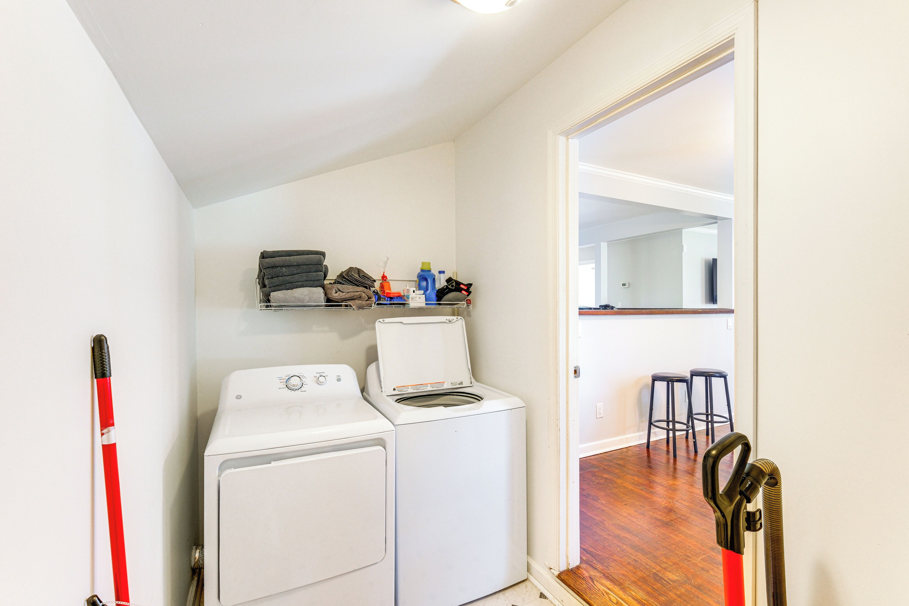 A laundry area with two washing machines, a drying rack, and a vacuum cleaner.