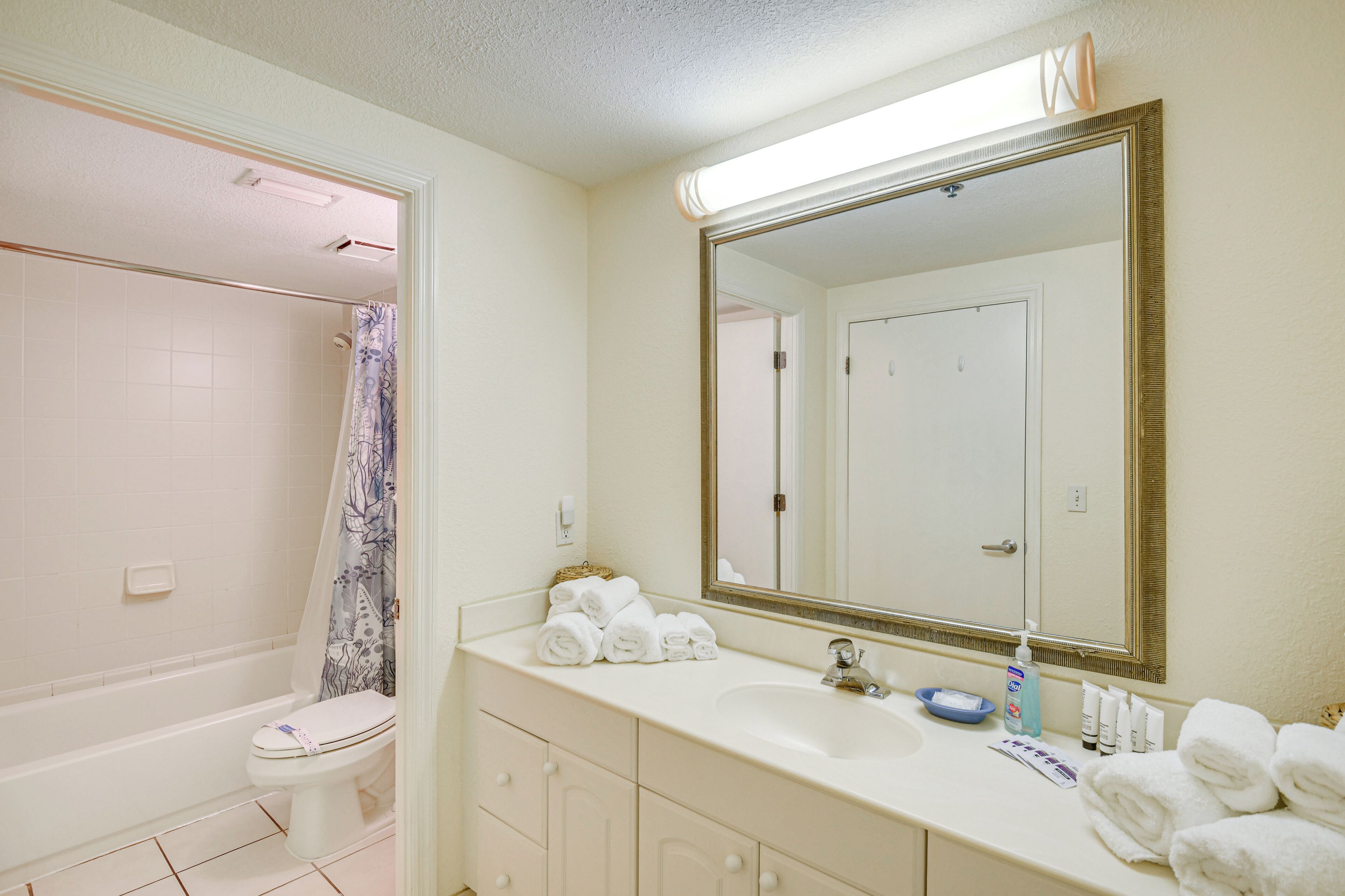 A bathroom with a bathtub, toilet, sink, and a large mirror.