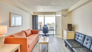Een woonkamer met een bank, een salontafel, een televisie en een bureau.