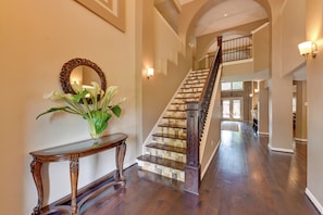 Stunning staircase leads to an upper level, flanked by a console table and ornate mirror.