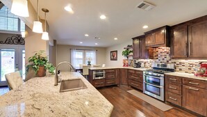 A modern kitchen with granite countertops, stainless steel appliances, and wooden cabinets. - Large Luxury Home With Saltwater Pool (Denton)