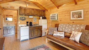 A wooden cabin interior with a kitchen, a dining area, and a living room with a leather sofa. - 1 Mi to Current River: Cozy Studio Cabin! (Van Buren)
