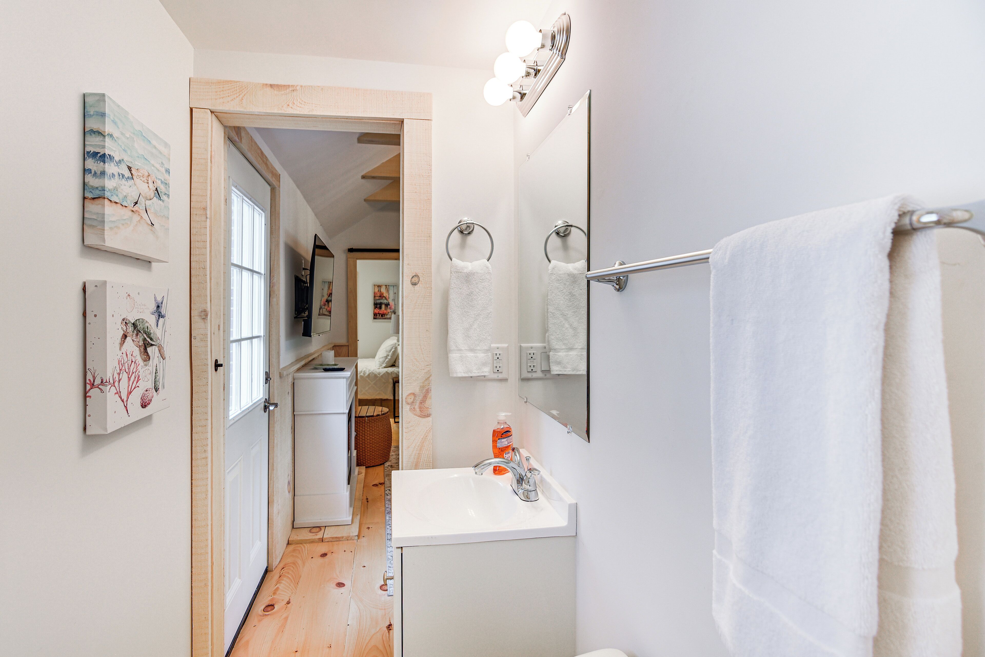 A bathroom with a white sink, a mirror, and a towel rack.