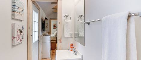 A bathroom with a white sink, a mirror, and a towel rack.