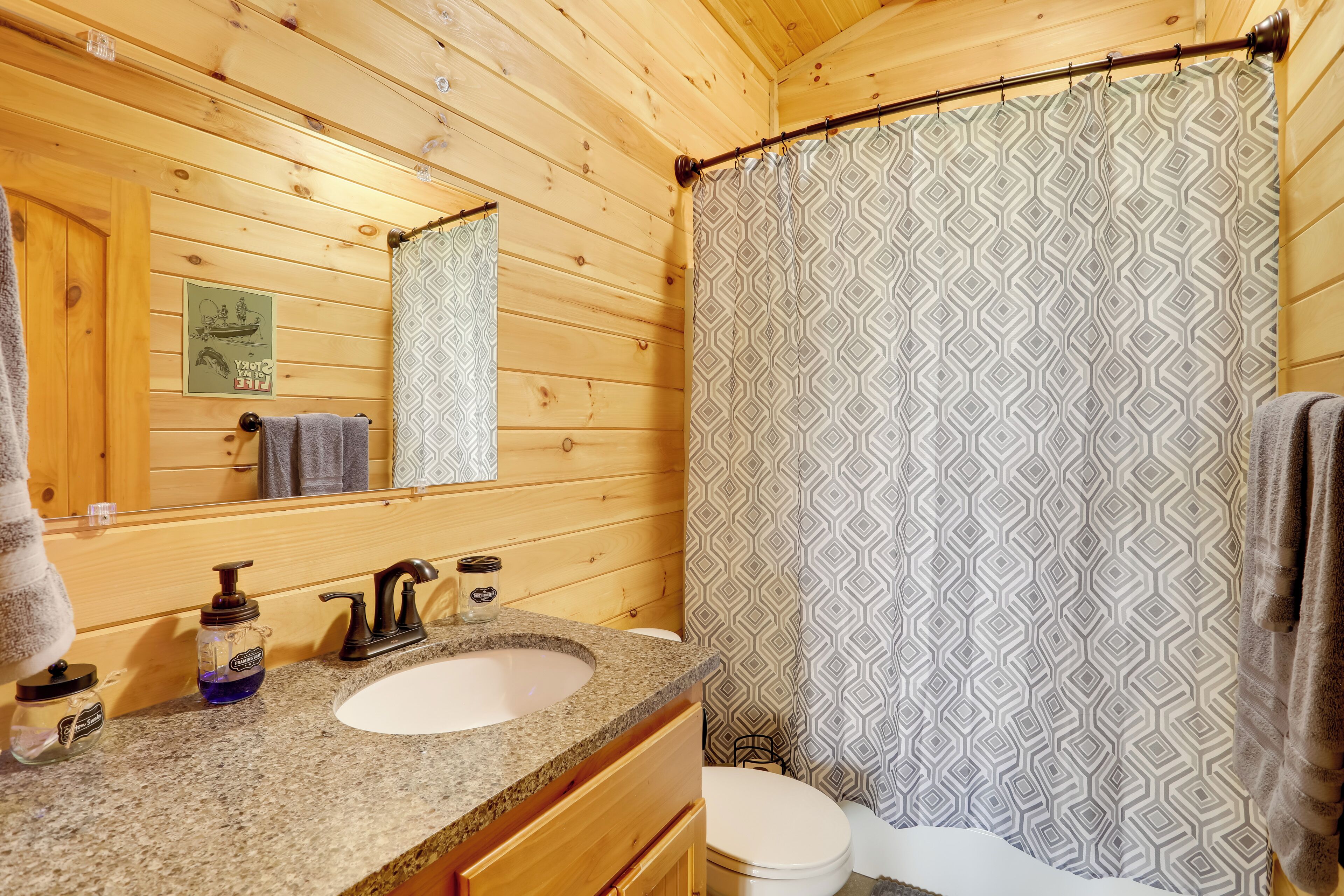 Une salle de bain rustique, aménagée dans une cabane en bois, avec un lavabo, un miroir et des toilettes.