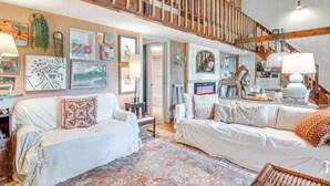 A spacious living room with two white sofas, a wooden staircase, and various wall art. - 4 Mi to Lake Santeetlah: Cabin w/ Deck & Views (Robbinsville)