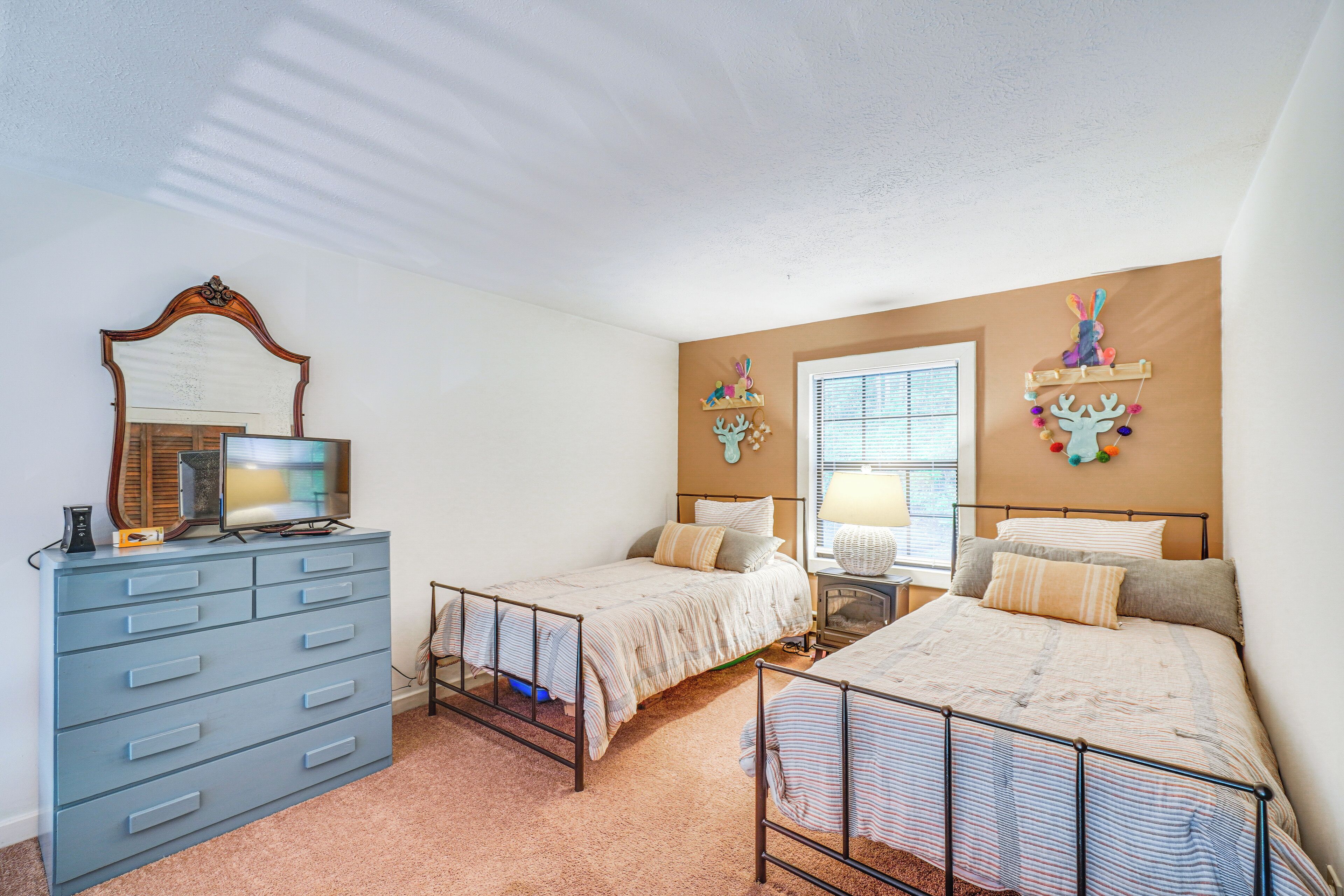 Un dormitorio con dos camas, un aparador, un espejo y decoración en la pared.