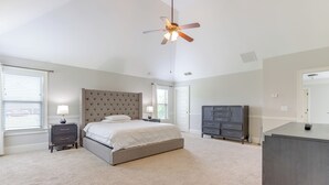 A bedroom with a bed, nightstands, a dresser, a ceiling fan, and a door. - 9 Mi to Trilith Studios: Gem in Fayetteville! (Fayetteville)
