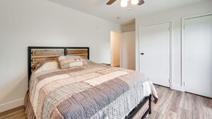 Een slaapkamer met een bed, een plafondventilator en witte deuren.