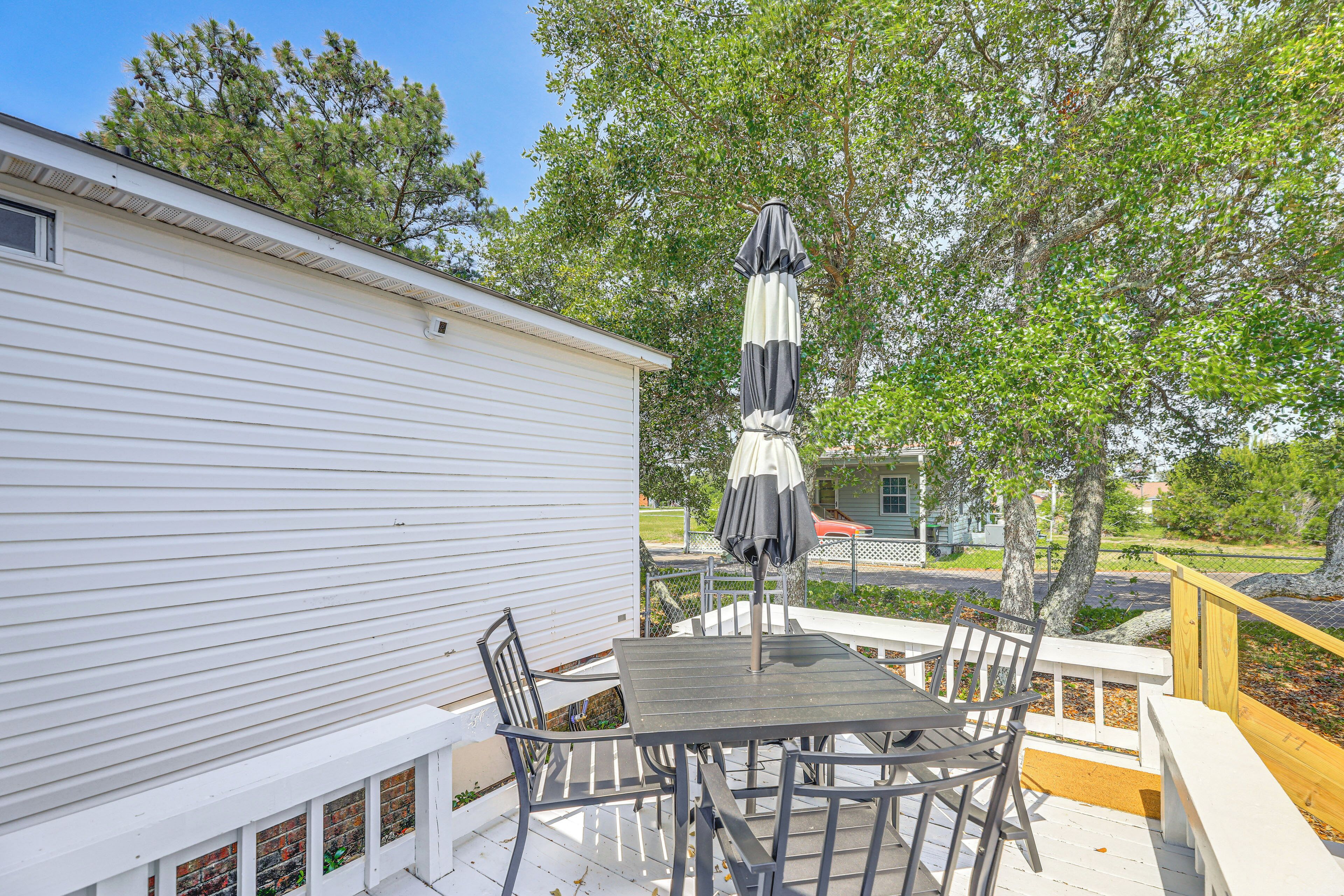A patio with a table and chairs, an umbrella, and a white building.