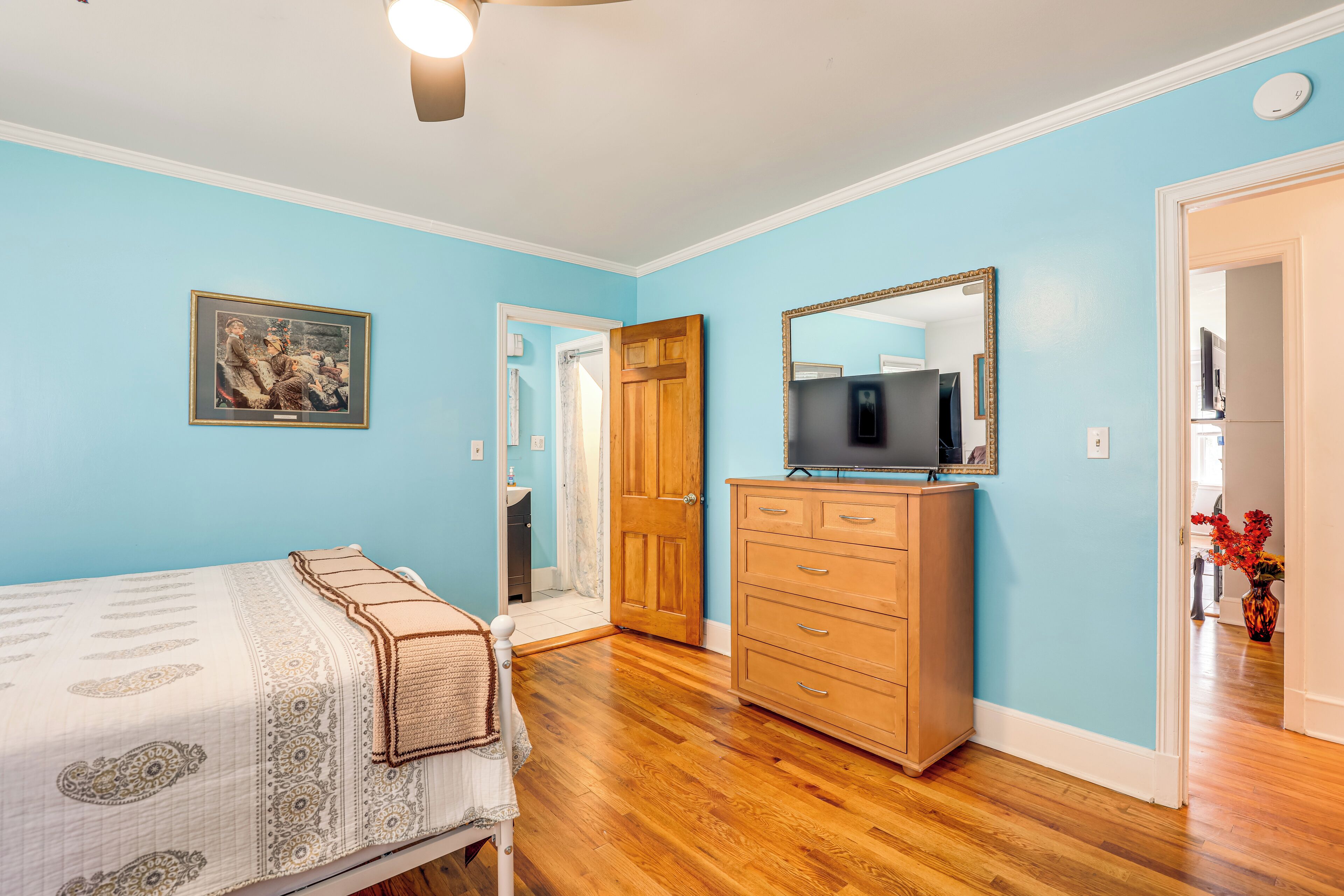 A bedroom with a bed, dresser, and a mirror.