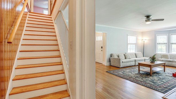 A staircase with wooden steps and a handrail, leading to a room with a ceiling fan, a sofa, and a coffee table. - Home 1 Mi to Dtwn Conway: Great for Beach Days! (Conway)