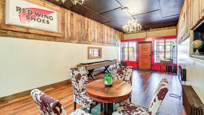 A dining area with a wooden table and chairs, a chandelier, and a sign reading "RED WING SHOES". - Walkable Townhome: 'M on Main' in Wytheville (Wytheville)