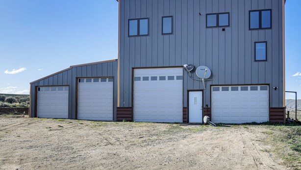 A two-story building with three garage doors and a satellite dish. - 5 Mi to Lake: Secluded Pinedale Retreat w/ Sauna! (Pinedale)