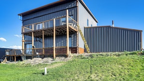Ein mehrgeschossiges Gebäude im Bau mit einer Holzterrasse und einer Metallfassade.