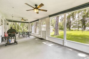 A covered patio with two ceiling fans, a grill, and a table with chairs.