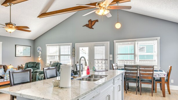 A modern kitchen with a central island, white cabinetry, and a ceiling fan. - Walk to Beach: Family Getaway By San Luis Pass! (Freeport)
