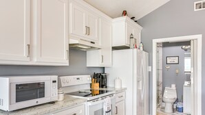 A modern kitchen with white cabinetry, a microwave, oven, and a refrigerator. - Walk to Beach: Family Getaway By San Luis Pass! (Freeport)