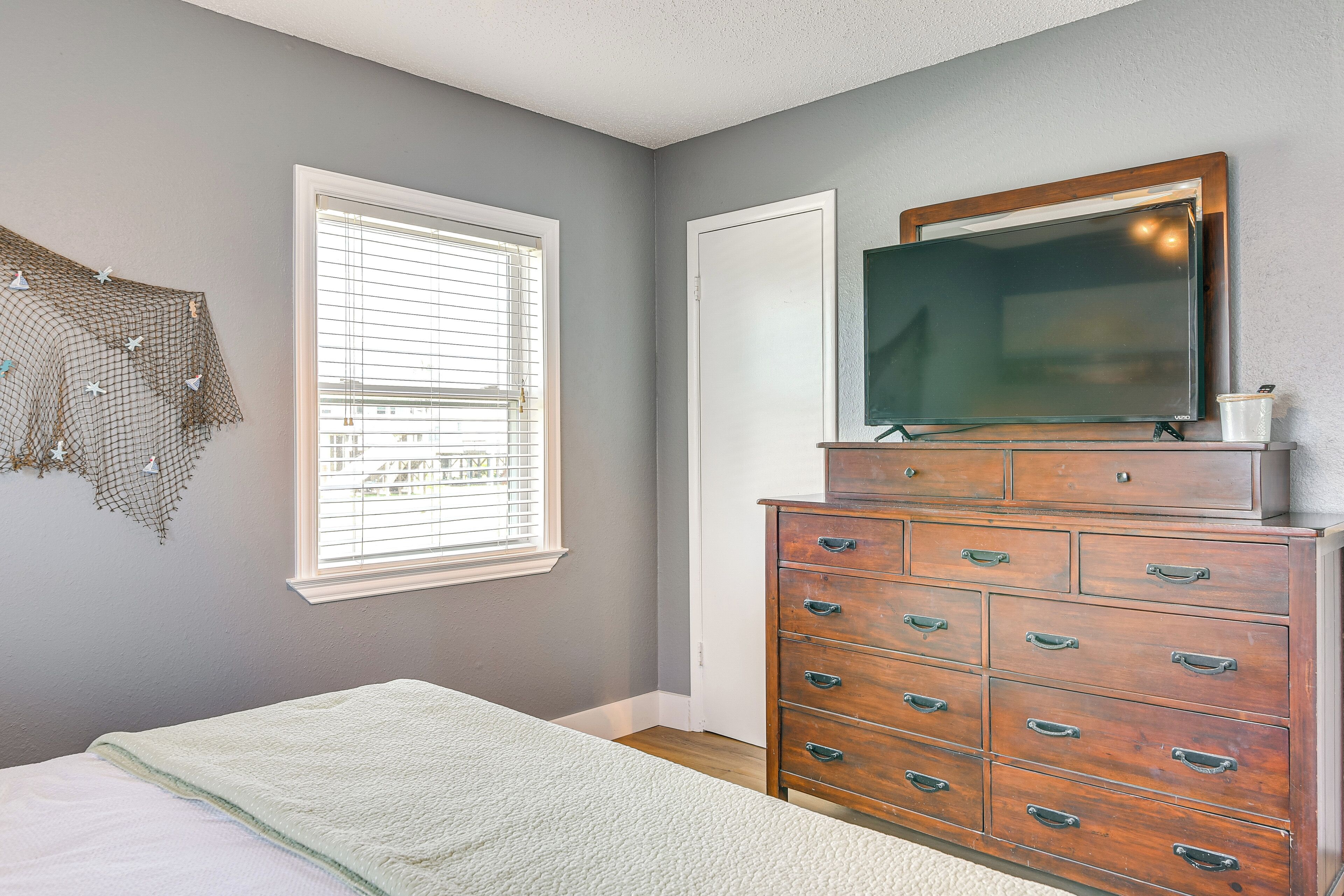 A bedroom with a bed, dresser, and a TV on top of the dresser.