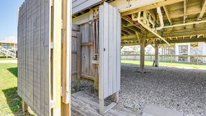 A wooden building with a covered porch and a gravel ground. - Walk to Beach: Family Getaway By San Luis Pass! (Freeport)
