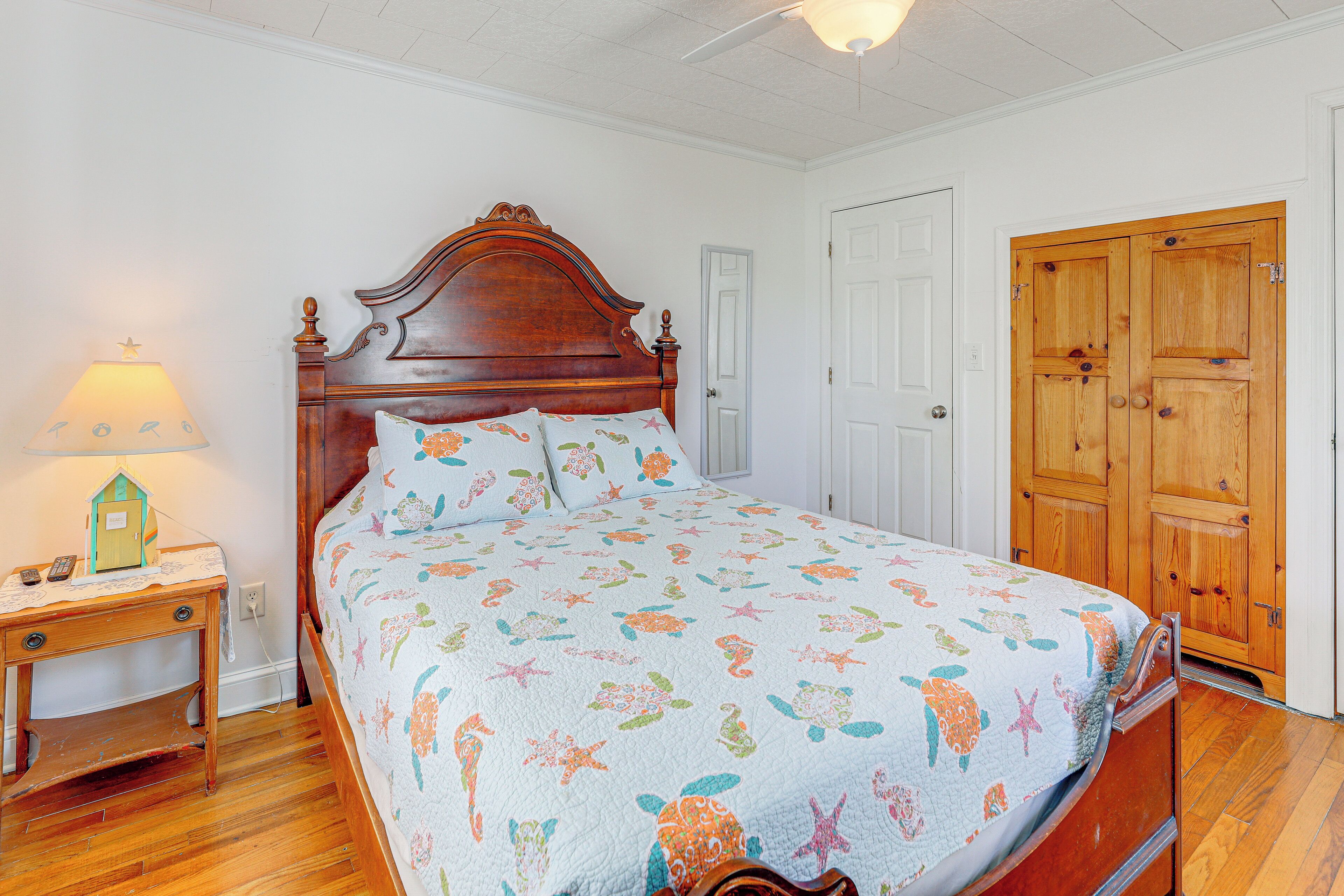A bedroom with a wooden bed, a nightstand with a lamp, and a wooden wardrobe.