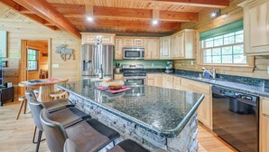 A spacious kitchen with granite countertops, wooden cabinets, and a large island with bar stools. - Game Room, Hot Tub & Decks: Scenic Franklin Cabin (Franklin)